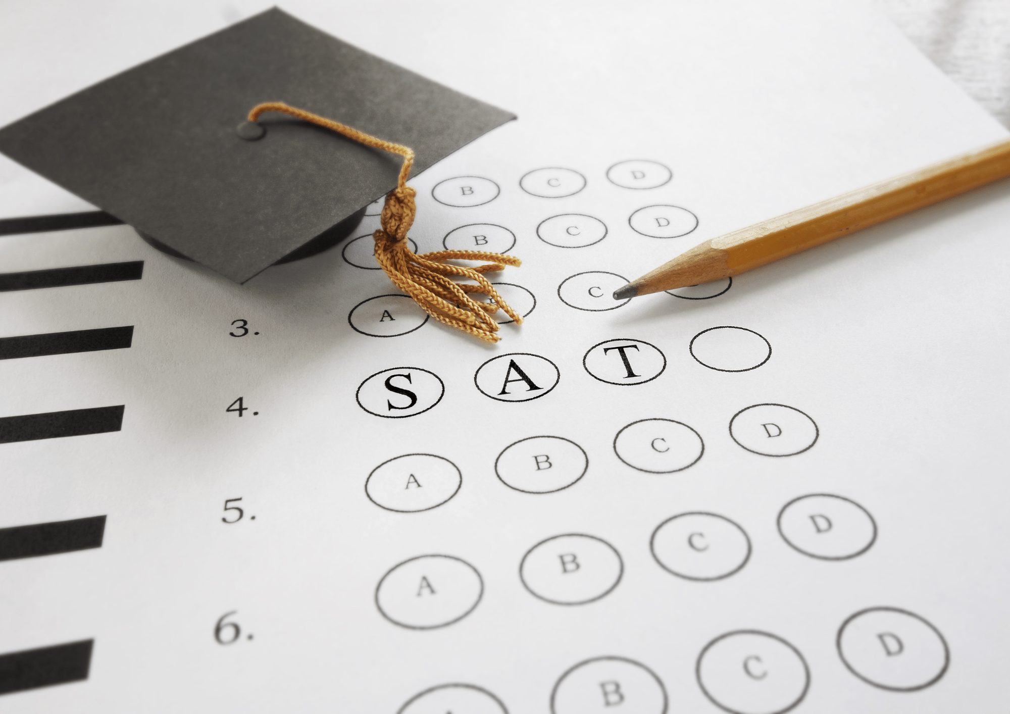The image shows a close-up of an SAT answer sheet with filled-in bubbles spelling “SAT”. A sharpened yellow pencil is pointing towards the answer choices, resting on the paper. A small black graduation cap with a golden tassel is placed on the left side of the answer sheet. The background is white and clean, focusing attention on the answer sheet, pencil, and graduation cap. The mood of the image suggests a connection between taking standardized tests like the SAT and academic achievement symbolized by the graduation cap. The text on the answer sheet reads, “3. A B C D, 4. S A T O, 5. A B C D, 6. A B C D”.